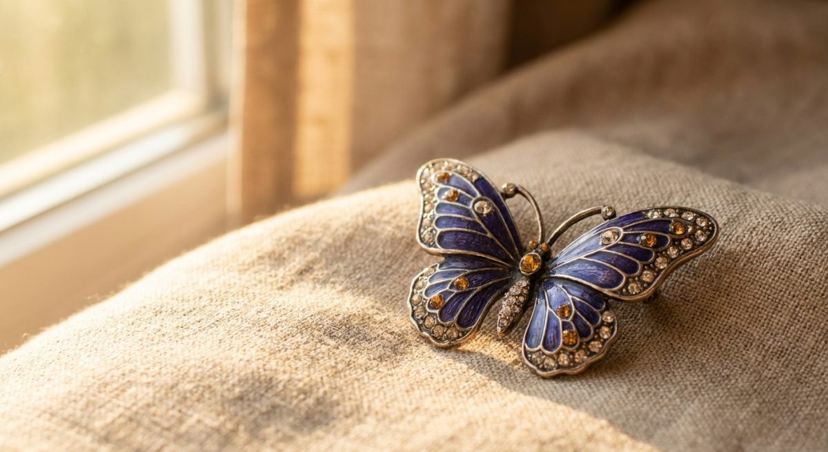 Broche papillon décorative en émail bleu profond avec strass, posée sur lin beige, lumière dorée de fin d'après-midi