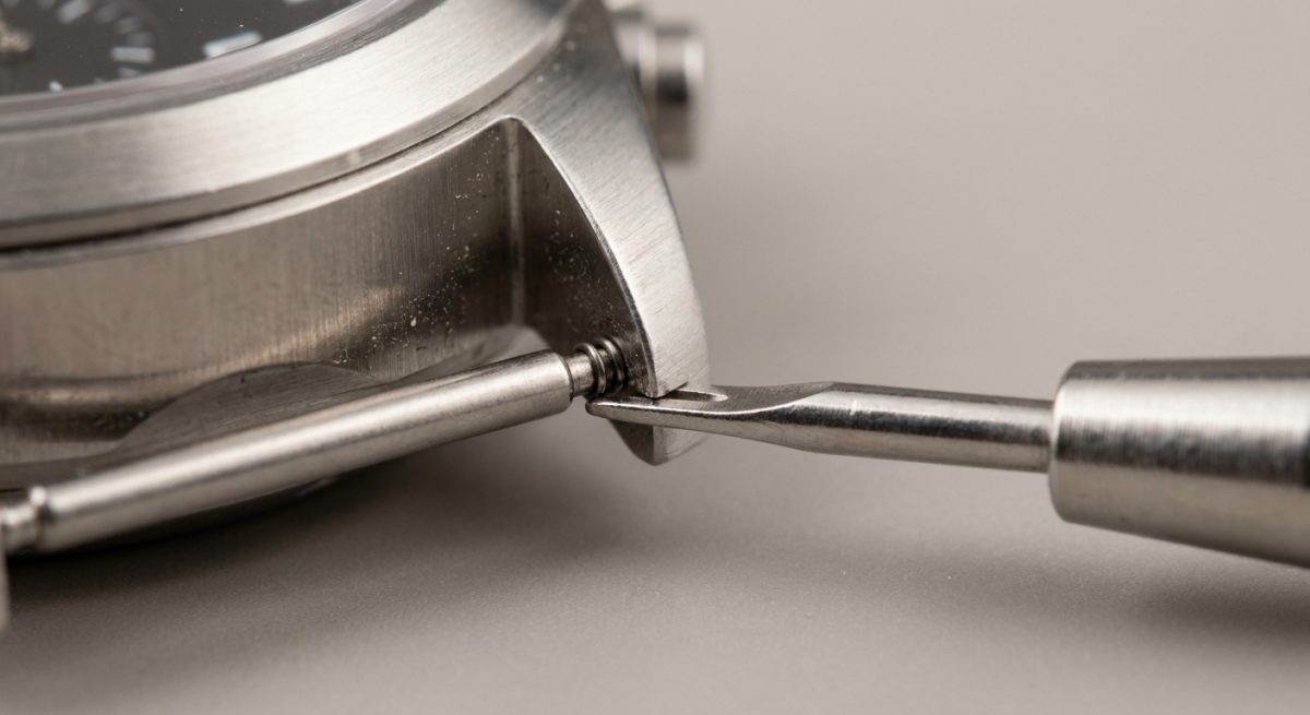 Outil à ergot comprimant une barrette à ressort entre les cornes d'une montre