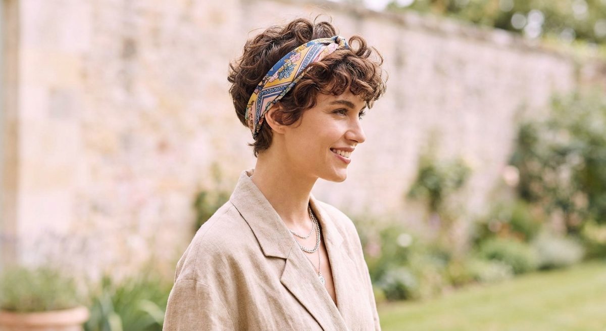 Femme souriante à la coupe pixie portant un foulard de soie en bandeau fin