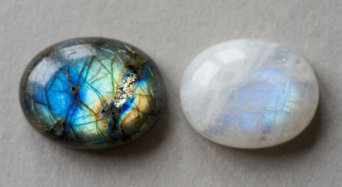 Cabochon de labradorite aux reflets bleu-or à côté d'une pierre de lune au voile blanc laiteux
