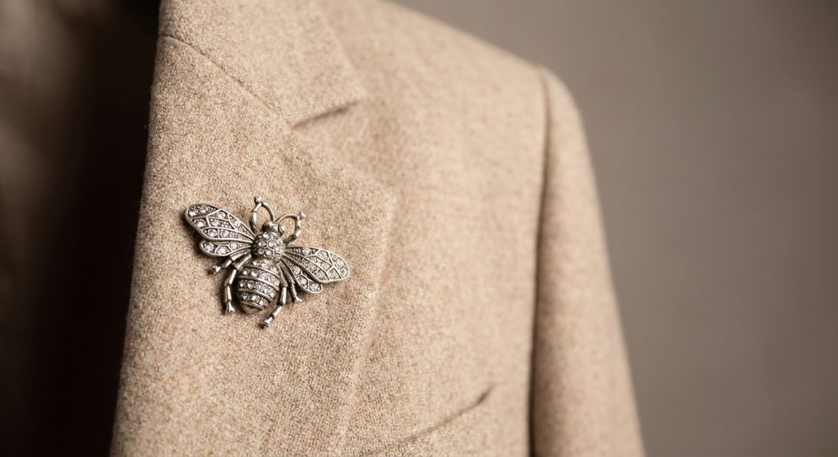 Broche abeille argentée à strass épinglée sur un revers de blazer beige
