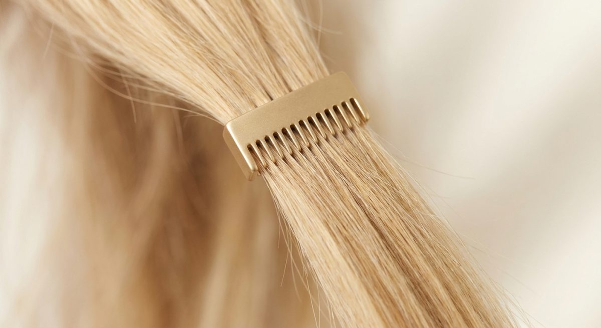 Détail macro de cheveux blonds fins retenus par un petit accessoire doré à dents rapprochées