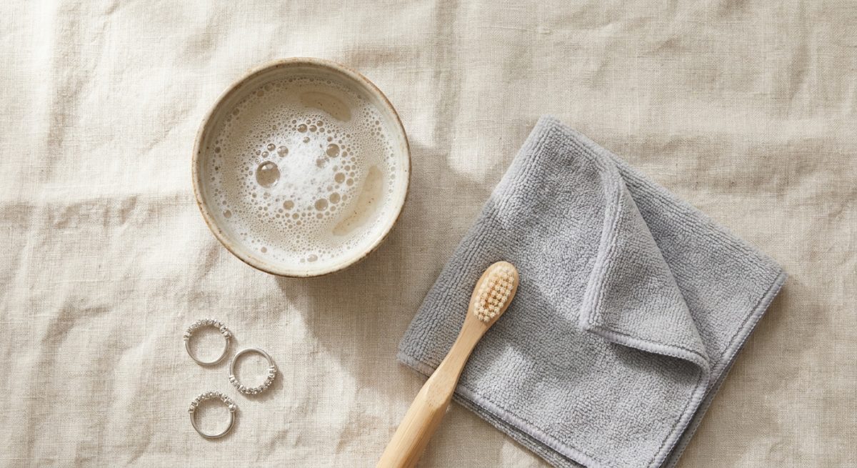 Bol d'eau savonneuse, brosse à dents souple et chiffon pour nettoyer une bague fantaisie